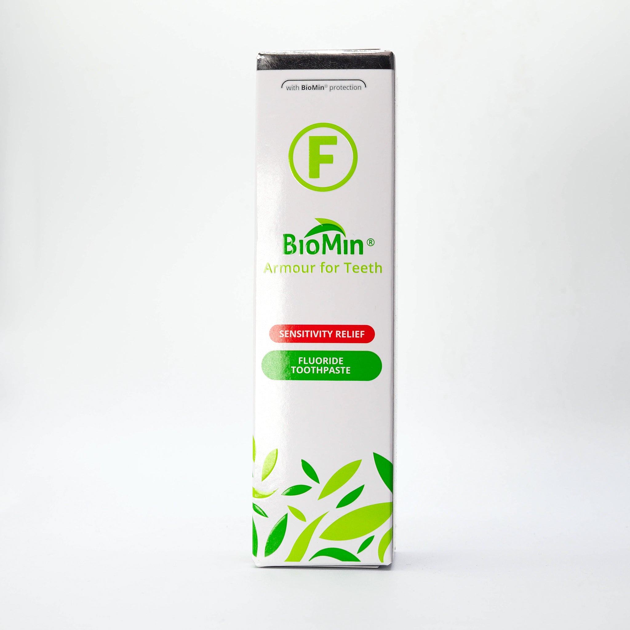A box of BioMin F toothpaste stands vertically, labeled "Armour for Teeth" with fluoride protection. The box features green leaf designs and a prominent green "F" symbol indicating fluoride content.