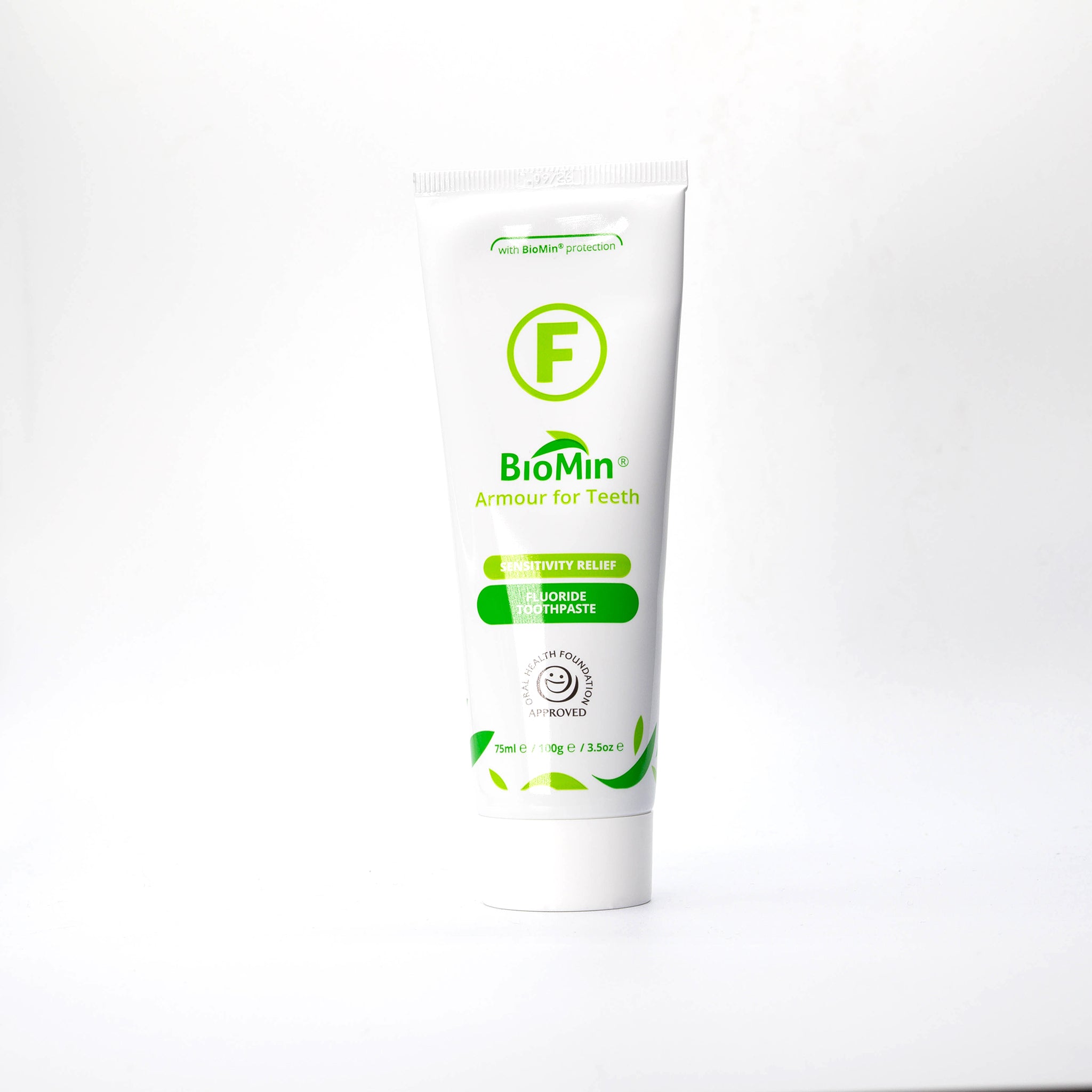 A white tube of BioMin F toothpaste labeled "Armour for Teeth" with fluoride protection. The tube features green leaf designs and a prominent green "F" symbol, indicating fluoride content.