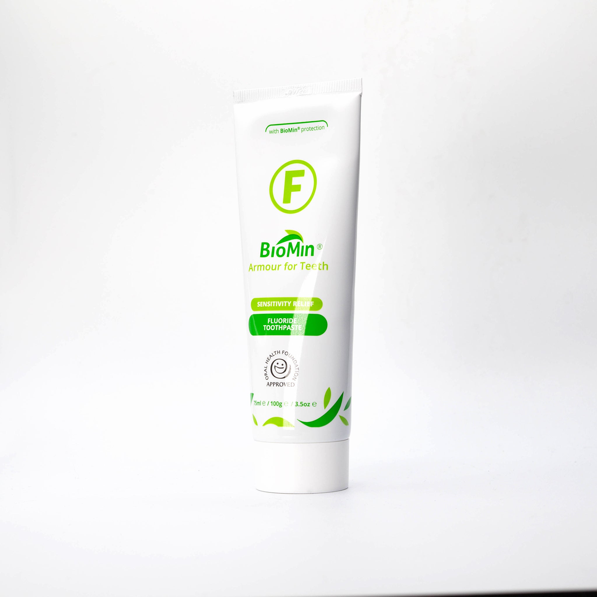 A white tube of BioMin F toothpaste, slightly turned to its left, labeled "Armour for Teeth" with fluoride protection. The tube features green leaf designs and a prominent green "F" symbol, indicating fluoride content.