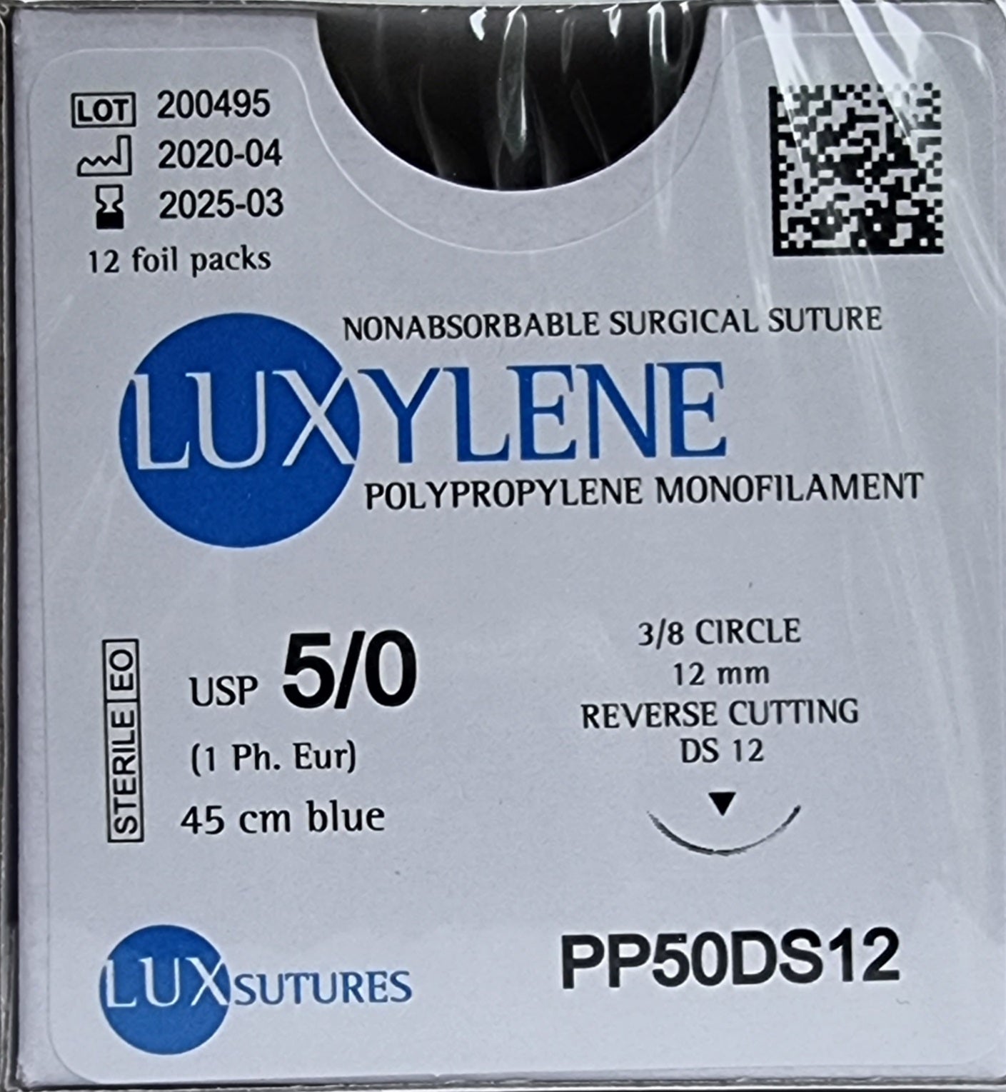 A close-up view of a box of Luxylene polypropylene monofilament non-absorbable surgical sutures. The label specifies USP 5/0 (1 Ph. Eur.), 45cm blue suture, and a 12mm 3/8 circle reverse cutting needle. The packaging is labeled as sterile EO and includes the lot number, manufacturing date, and expiration date.